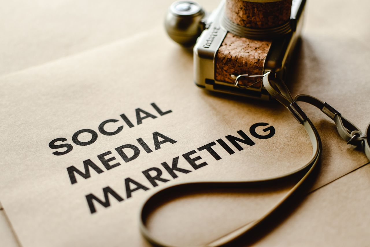 Gros plan d’un appareil photo posé sur du papier brun avec le texte Social Media Marketing, mettant en avant les thèmes du marketing numérique.